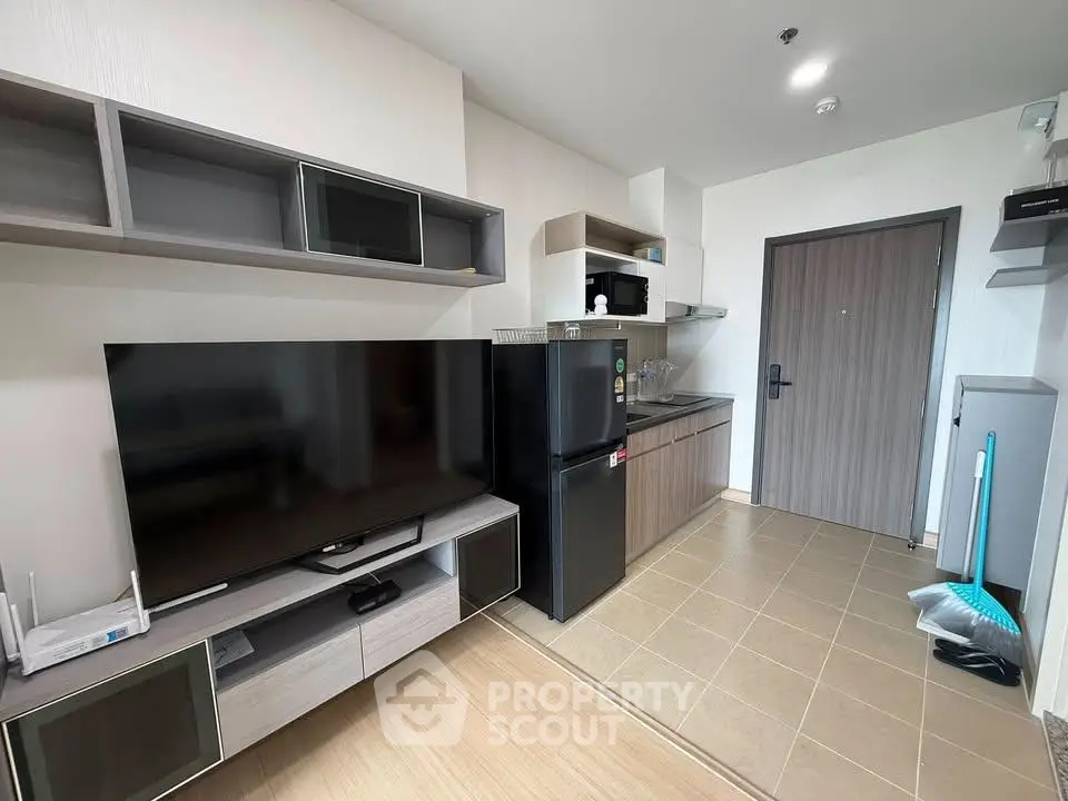 Modern apartment interior with sleek kitchen and entertainment area, featuring a large TV and stylish storage.