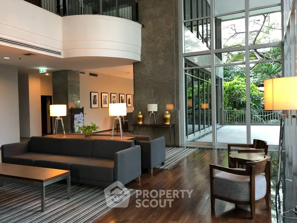 Luxurious lobby with modern furniture and large windows overlooking lush greenery.