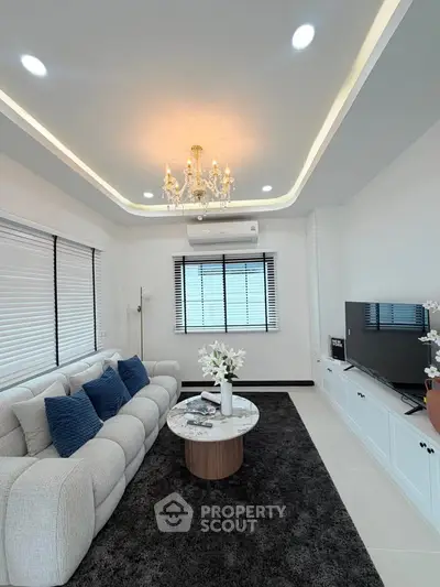 Elegant living room with modern decor, featuring a plush sofa, chic chandelier, and stylish entertainment unit.