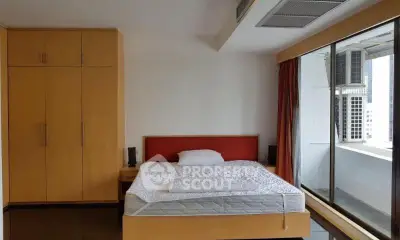 Spacious bedroom with large window and built-in wardrobe in modern apartment.