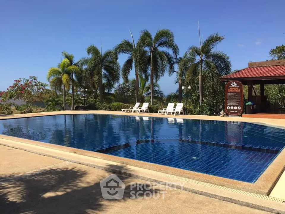 Luxurious outdoor pool with palm trees and sun loungers in tropical resort setting.