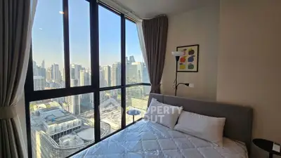 Modern bedroom with stunning city view through large windows in high-rise apartment.