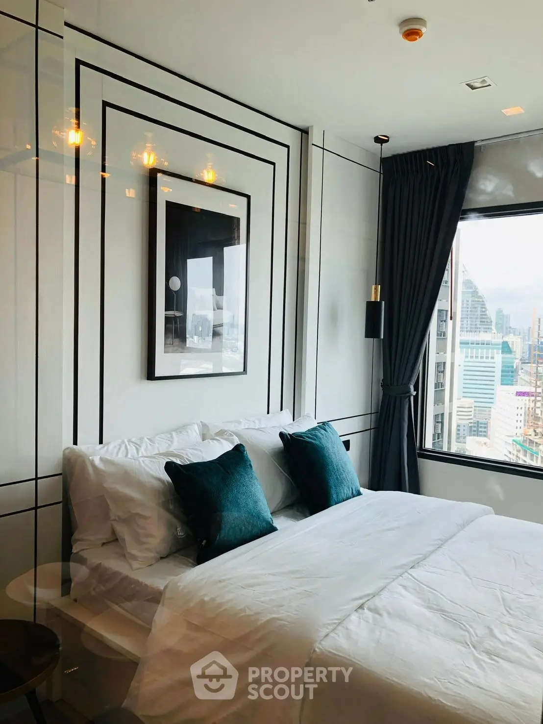 Luxurious bedroom with city view, elegant decor, and plush bedding in a high-rise apartment.