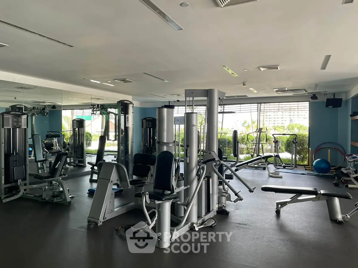Spacious modern gym with state-of-the-art equipment and large windows offering a scenic view.