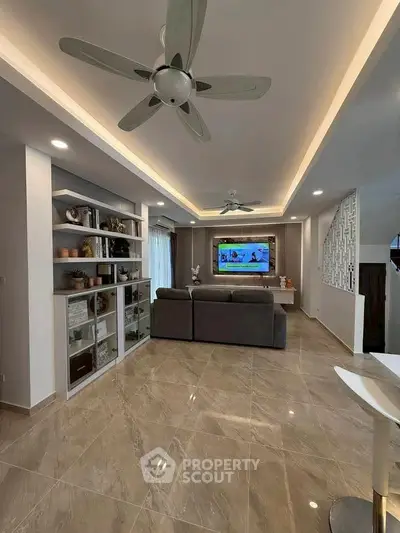 Spacious modern living room with elegant ceiling fans and stylish shelving, perfect for relaxation and entertainment.
