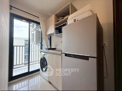 Modern kitchen with balcony access, featuring a washing machine and fridge in a compact layout.