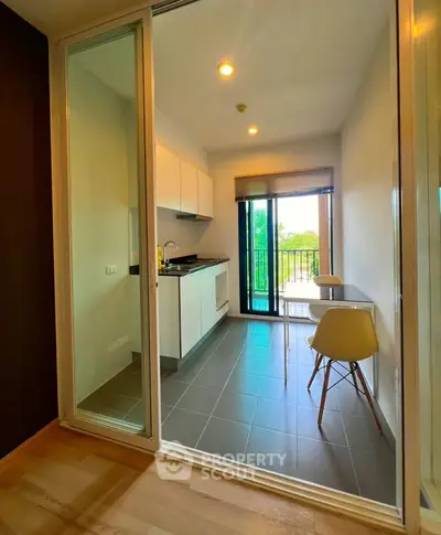 Modern kitchen with open layout and balcony view, featuring sleek cabinetry and stylish dining area.