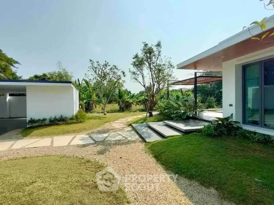 Modern home with lush garden and spacious outdoor area, featuring sleek architecture and serene surroundings.