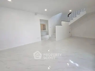 Spacious modern living room with sleek white tiles and elegant staircase.