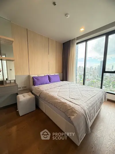 Modern bedroom with city view and stylish decor in high-rise apartment.