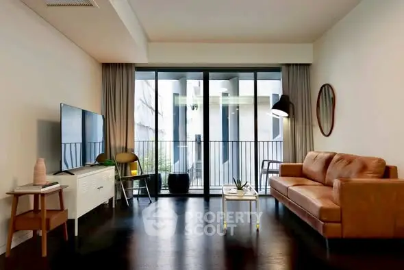 Modern living room with sleek furniture and balcony access, featuring a stylish sofa and large TV.