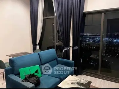 Modern living room with city view, blue sofa, and elegant curtains.