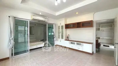 Spacious living room with modern design and large glass doors leading to bedroom