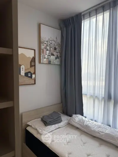 Cozy bedroom with natural light and modern decor, featuring a comfortable bed and stylish artwork.