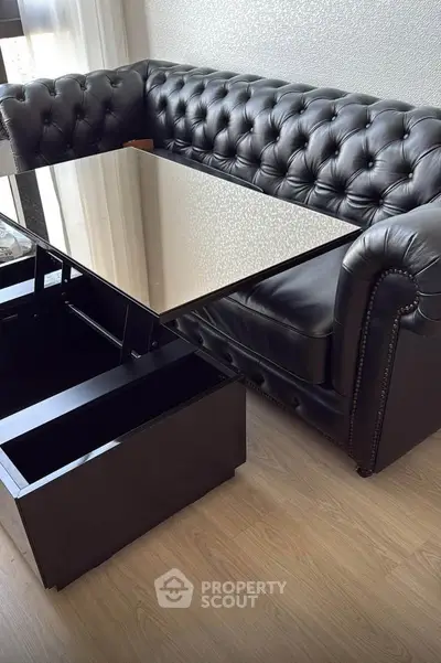 Luxurious black leather sofa with sleek glass coffee table in modern living room.