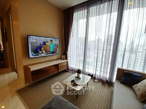 Modern living room with large window and city view, featuring a wall-mounted TV and stylish furniture.