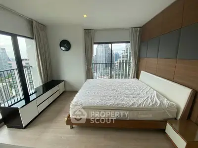Modern bedroom with city view, featuring a stylish bed and sleek furniture.