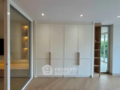 Spacious modern living room with large windows and elegant built-in storage cabinets.