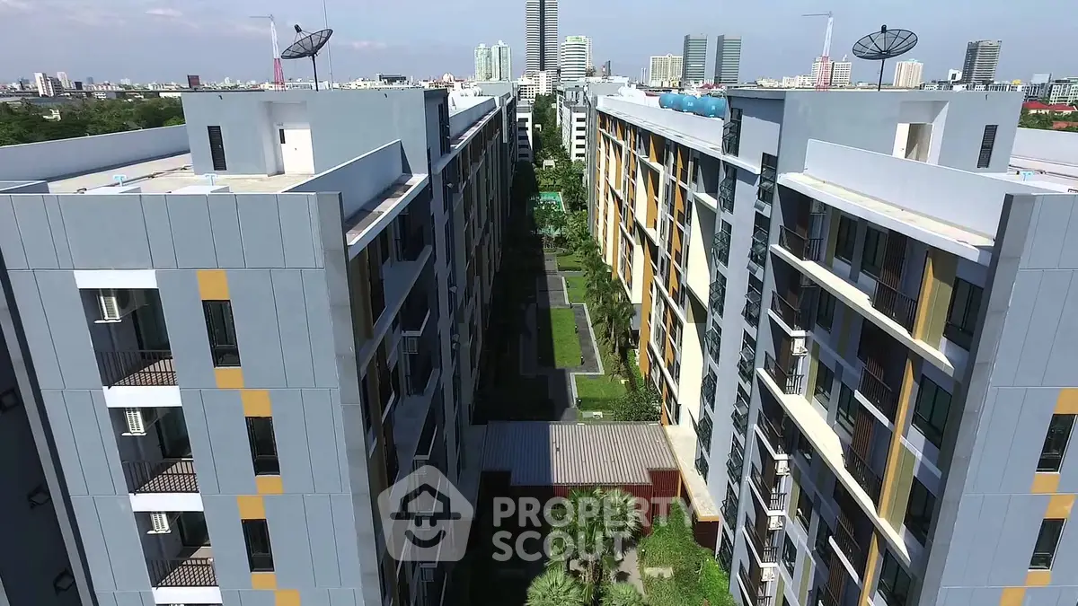 Modern apartment complex with lush courtyard and city skyline view.