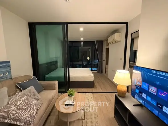 Modern living room with cozy sofa, stylish decor, and view into bedroom through glass partition.