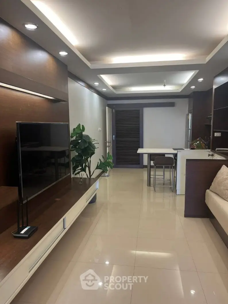 Modern living room with sleek design and open layout, featuring a wall-mounted TV and stylish lighting.