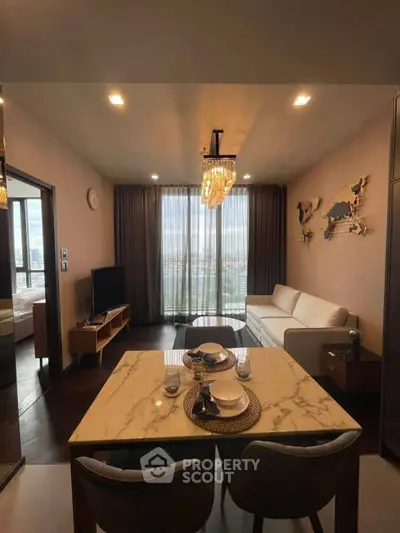 Elegant living room with city view, modern furniture, and stylish chandelier in a high-rise apartment.