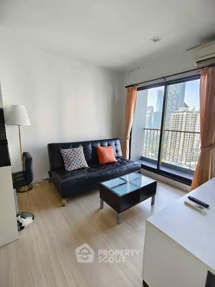 Modern living room with city view, featuring sleek black sofa and stylish decor.