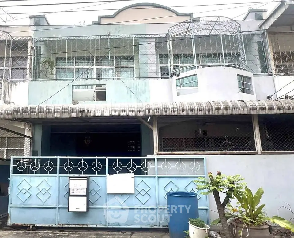 Charming two-story residential building with unique architectural features and gated entrance.