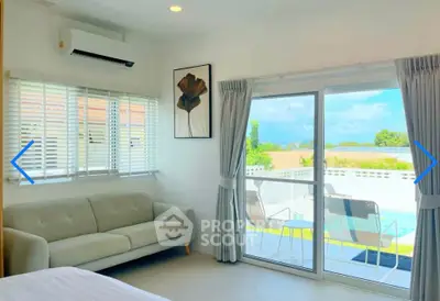 Bright living room with pool view, modern sofa, and large sliding glass doors leading to balcony.