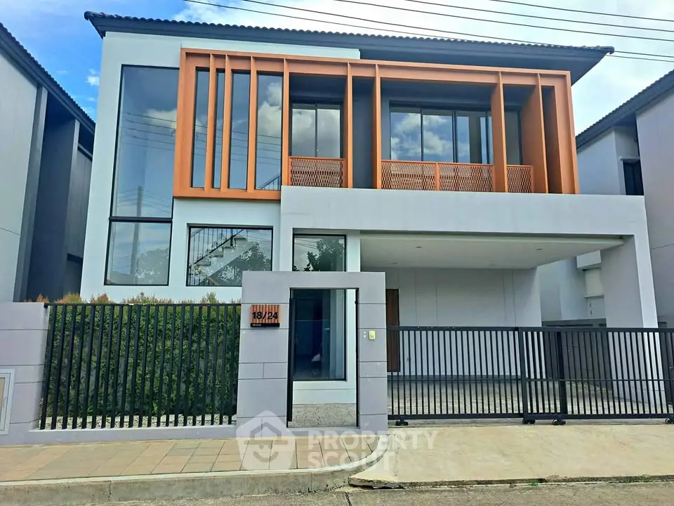 Modern two-story house with unique architectural design and gated entrance.
