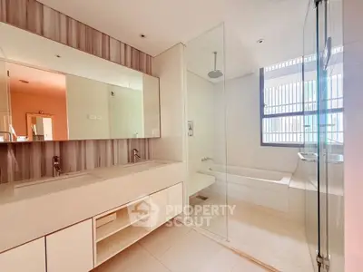 Spacious modern bathroom with glass shower and bathtub, featuring elegant fixtures and ample natural light.