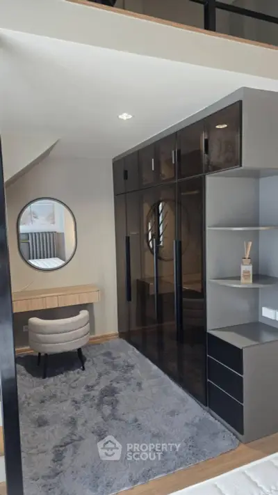 Stylish modern bedroom with sleek black wardrobe and cozy seating area.