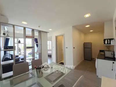 Modern open-plan living and dining area with kitchen, featuring sleek design and natural light.