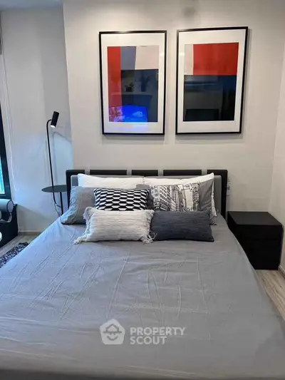 Modern bedroom with stylish decor and contemporary art above the bed, creating a cozy and inviting atmosphere.