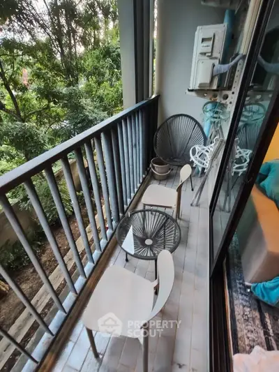 Charming balcony with modern seating and lush green view, perfect for relaxation.
