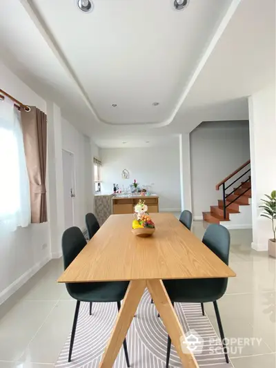 Modern dining room with elegant wooden table and stylish chairs in a bright open space.