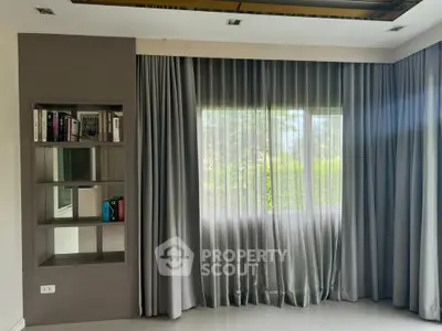 Elegant living room with large window and built-in bookshelf, featuring modern curtains and sleek flooring.