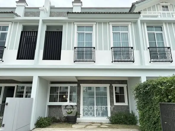 Charming two-story townhouse with modern facade and lush greenery