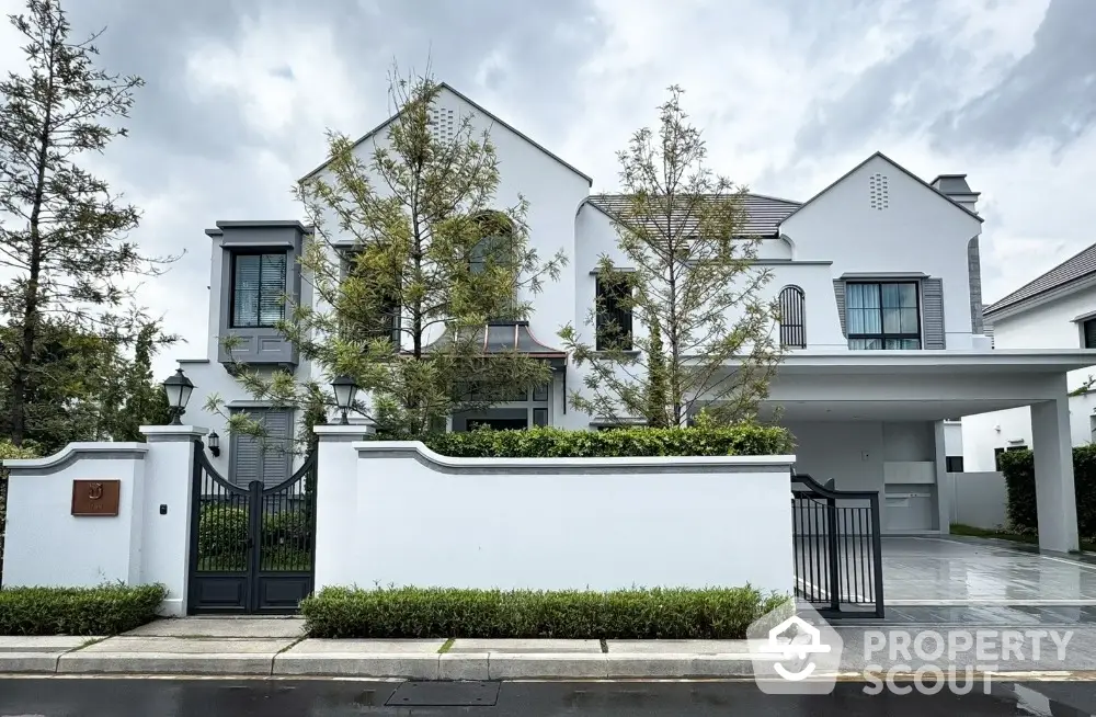 Elegant modern white house with lush landscaping and spacious driveway in upscale neighborhood.