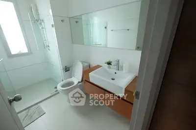 Modern bathroom with glass shower and sleek vanity in a contemporary home.