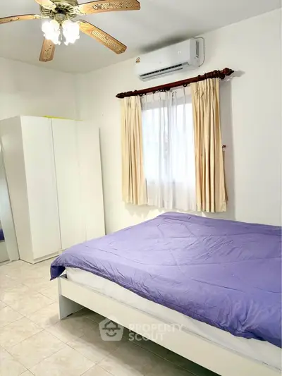 Cozy bedroom with air conditioning and natural light, featuring a comfortable bed and wardrobe.