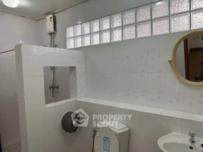 Spacious bathroom with modern fixtures and glass block window for natural light.
