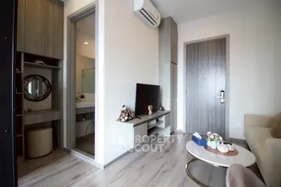 Modern living room with stylish decor and open view to bathroom, featuring sleek furniture and wooden flooring.