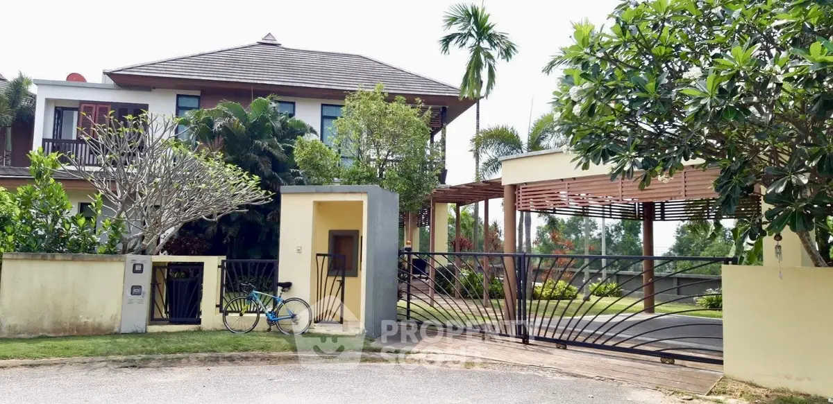 Luxurious modern villa with lush garden and spacious driveway in tropical setting.