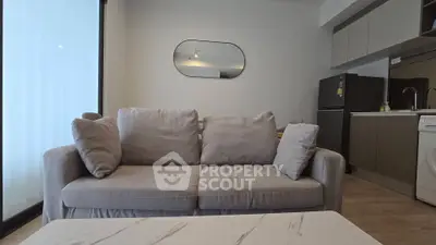 Modern living room with cozy sofa and sleek kitchen appliances in open layout apartment.