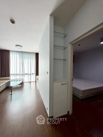 Modern apartment interior with spacious living room and bedroom, featuring sleek wooden flooring.