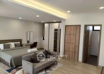 Spacious modern bedroom with stylish decor and cozy seating area, perfect for relaxation.