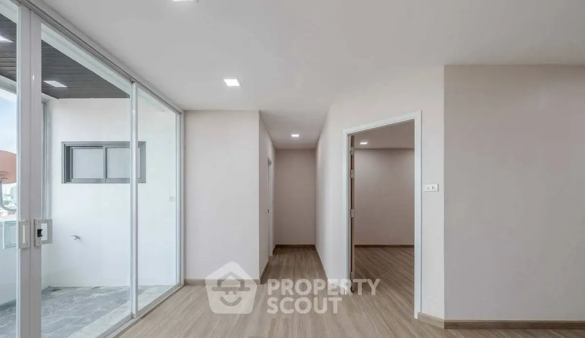 Spacious modern apartment interior with sleek wooden flooring and large windows for natural light.