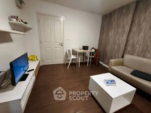 Cozy living room with modern decor and wooden flooring, featuring a TV, sofa, and dining area.