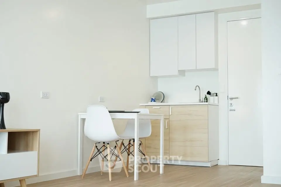 Modern minimalist kitchen with white cabinets and wooden accents in a cozy apartment.